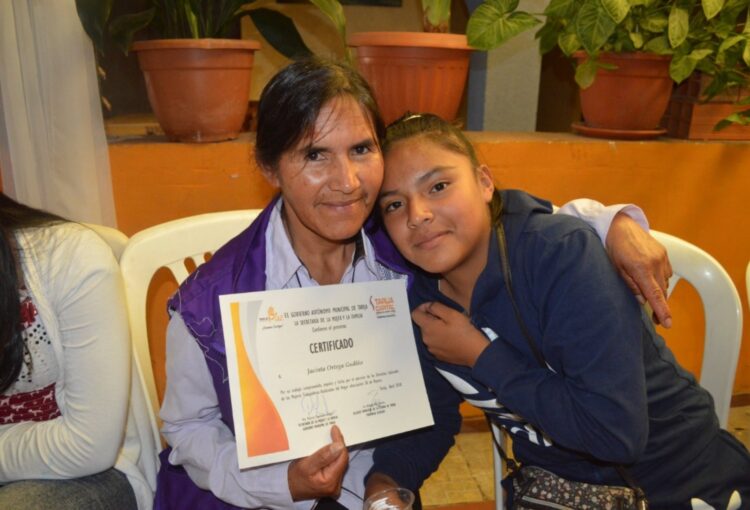 Jacinta Ortega junto a su hija muestra su certificado como trabajadora del hogar. Foto: Acceso.